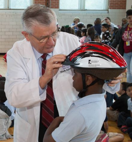 Dr. Kubala fits a helmet on a child during a Hard Hats for Little Heads event.